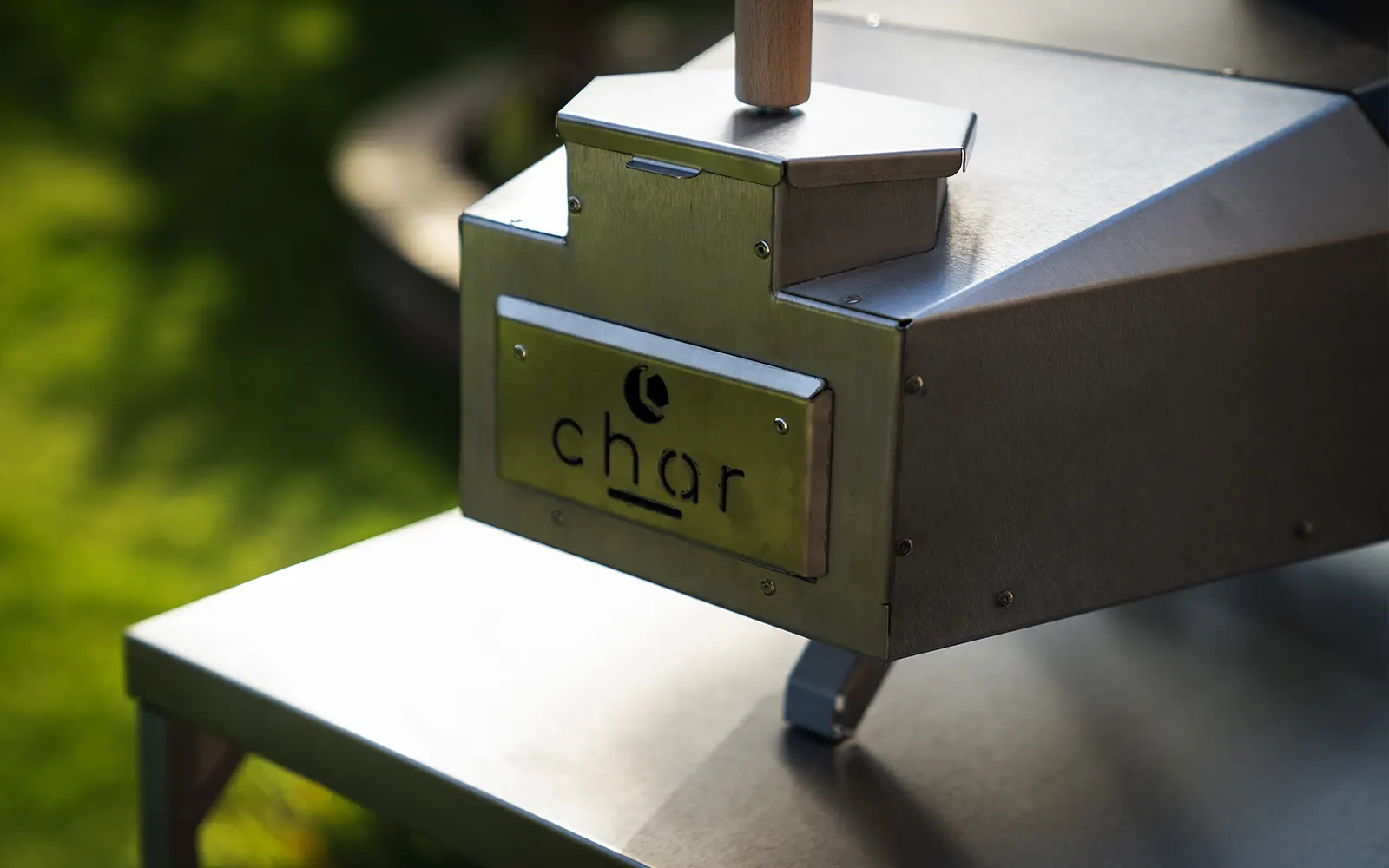 Pizza oven on a stainless steel table in a garden setting