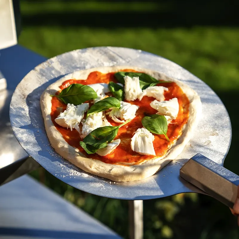 Close-up of an uncooked pizza on a pizza peel ready to put into the pizza oven