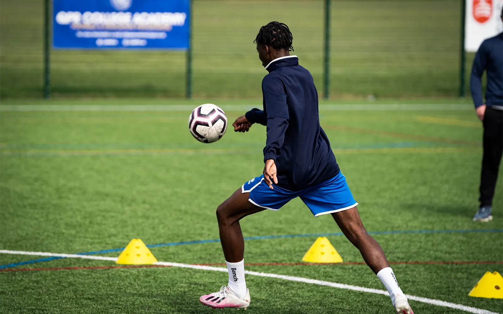 An action shot of a teenage boy during a football training session at a football pitch