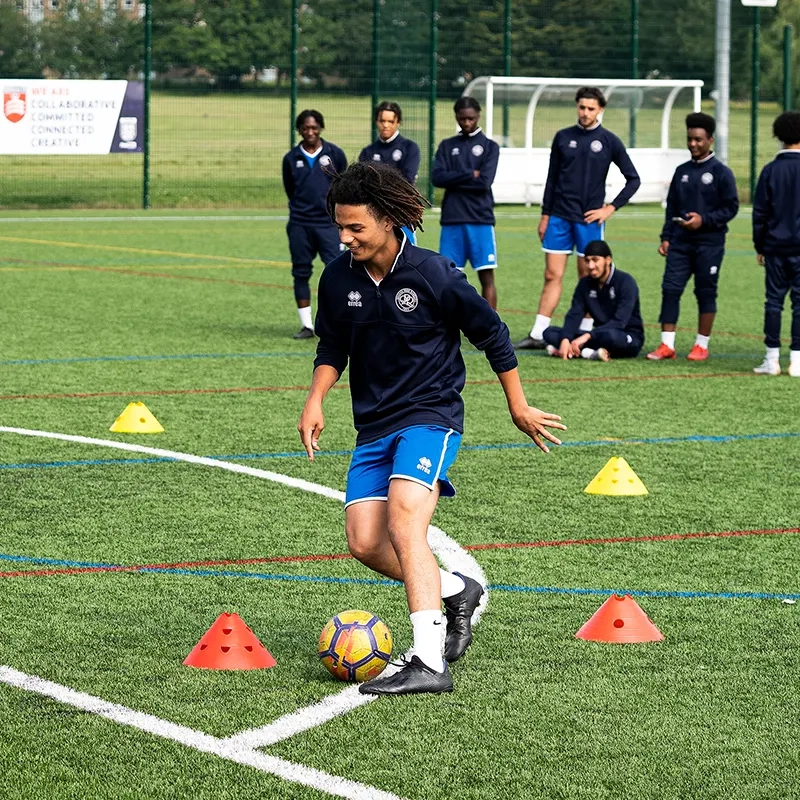 An action shot of a teenage boy during a football training session at a football pitch