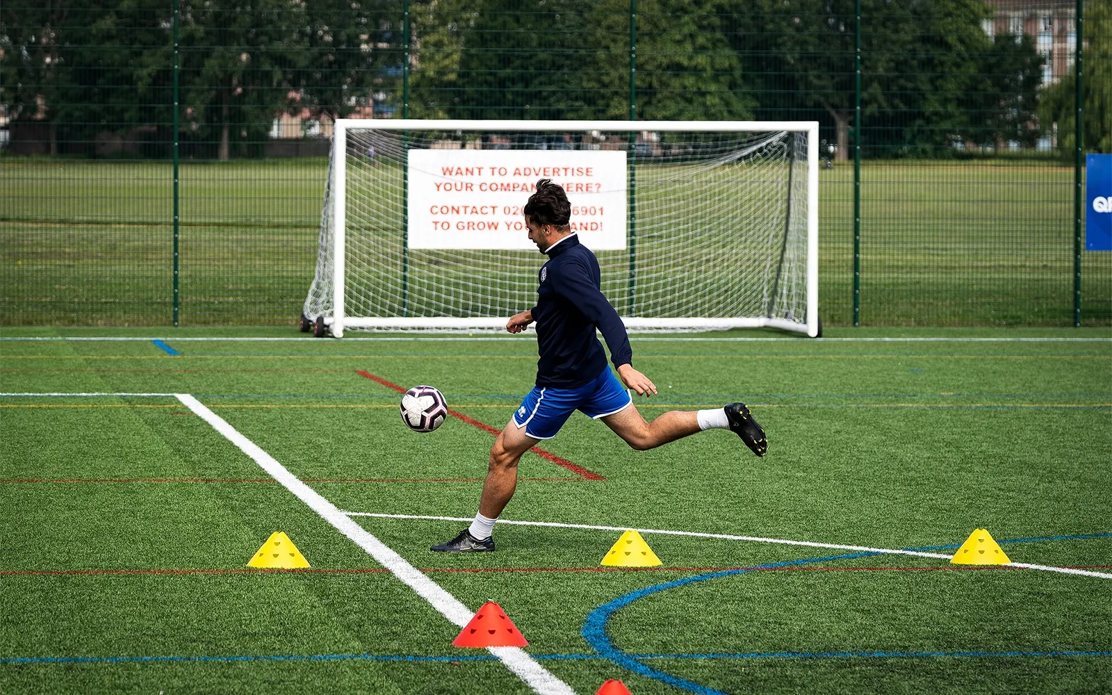 An action shot of a teenage boy during a football training session at a football pitch