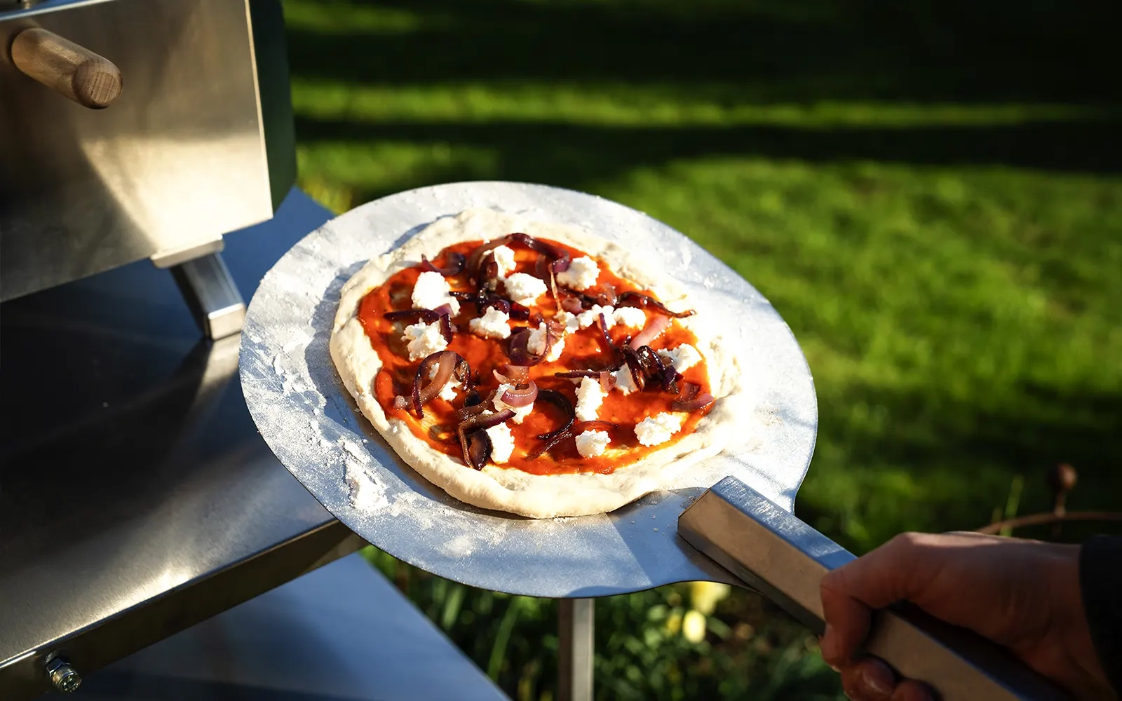 Close-up of an uncooked pizza on a pizza peel ready to put into the pizza oven