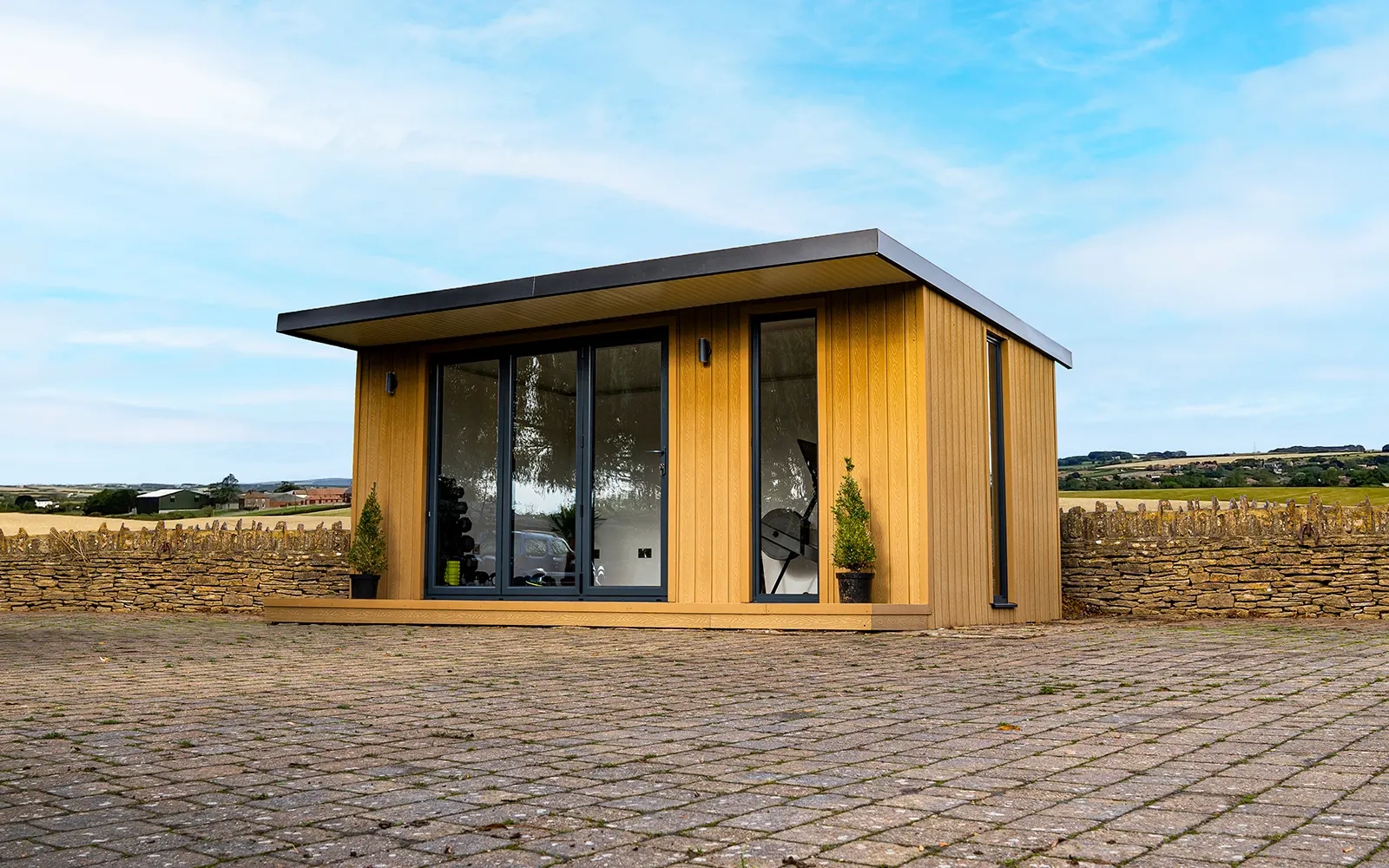 A garden room on a paved courtyard with a vivid blue sky in the background