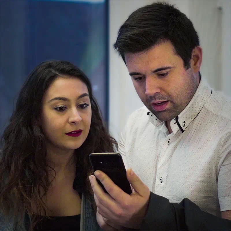 A still from the ‘Trunk’ music video showing a young couple anxiously staring at a mobile phone
