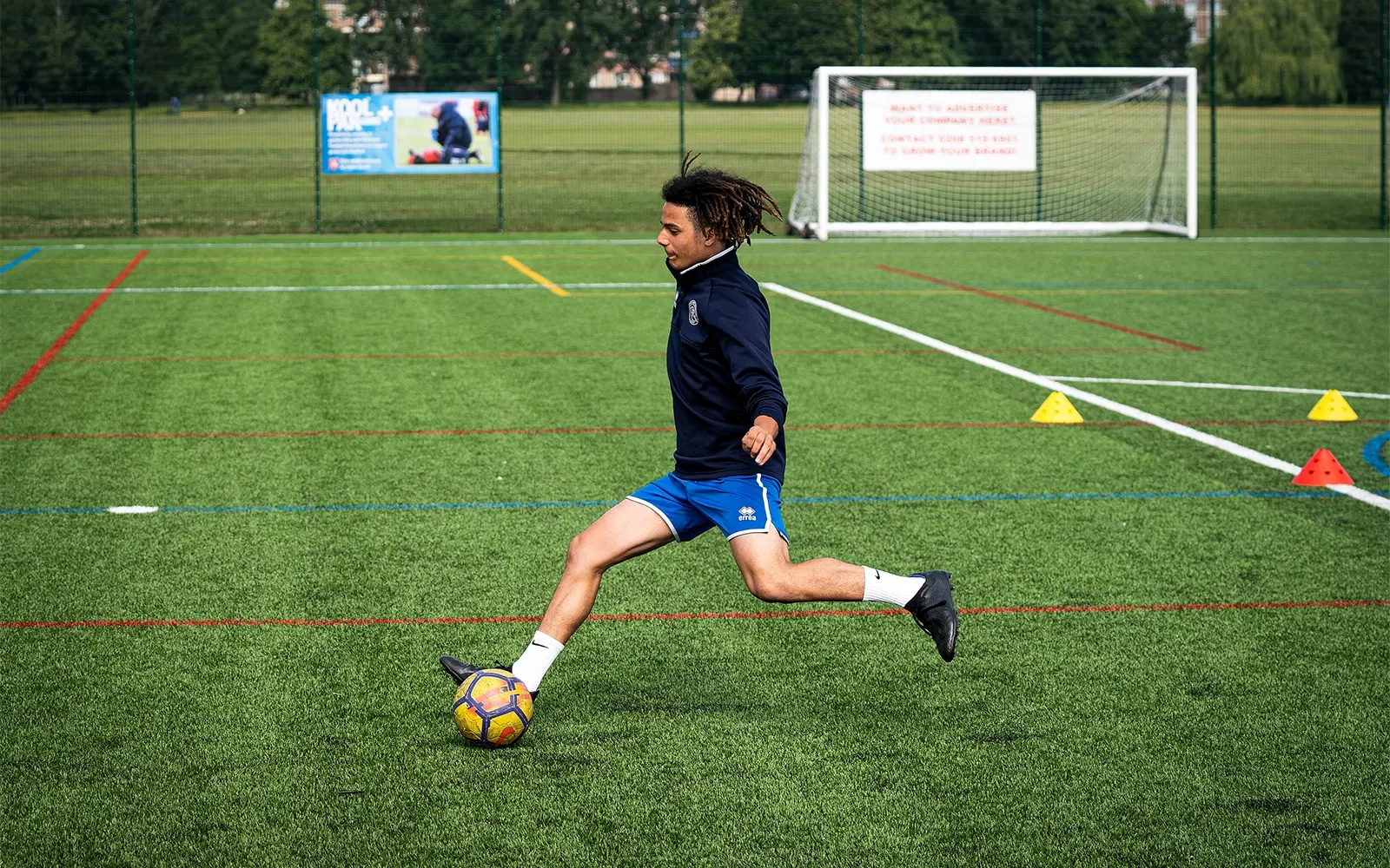 An action shot of a teenage boy during a football training session at a football pitch