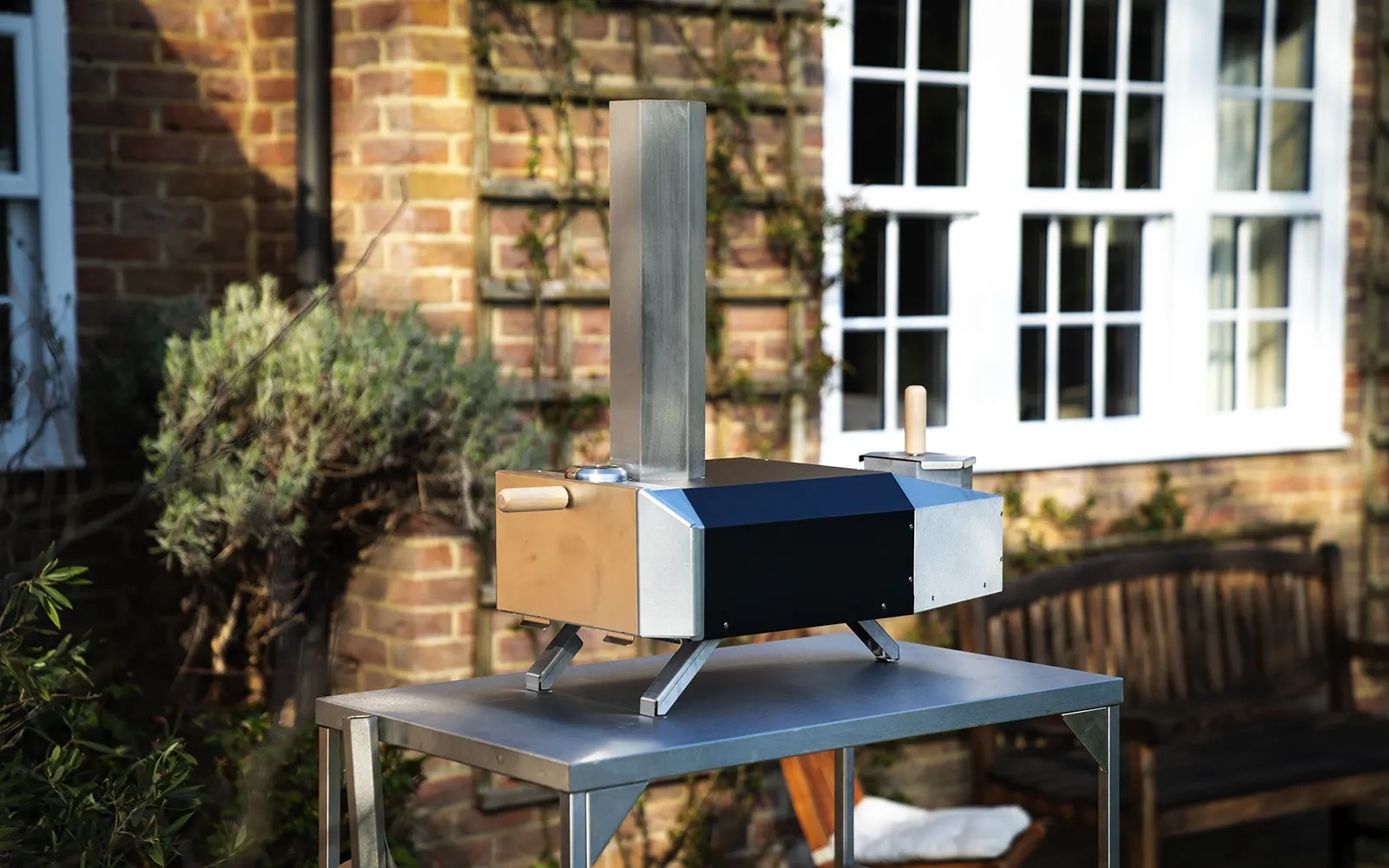Pizza oven on a stainless steel table in a garden setting