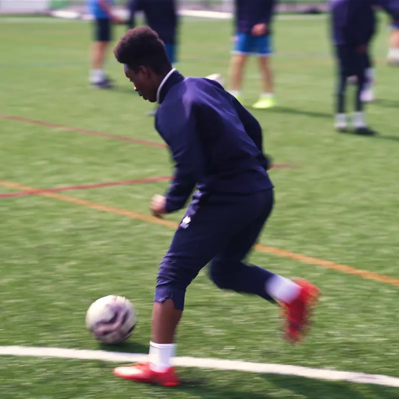 An action shot of a teenage boy about to kick an football on a football pitch