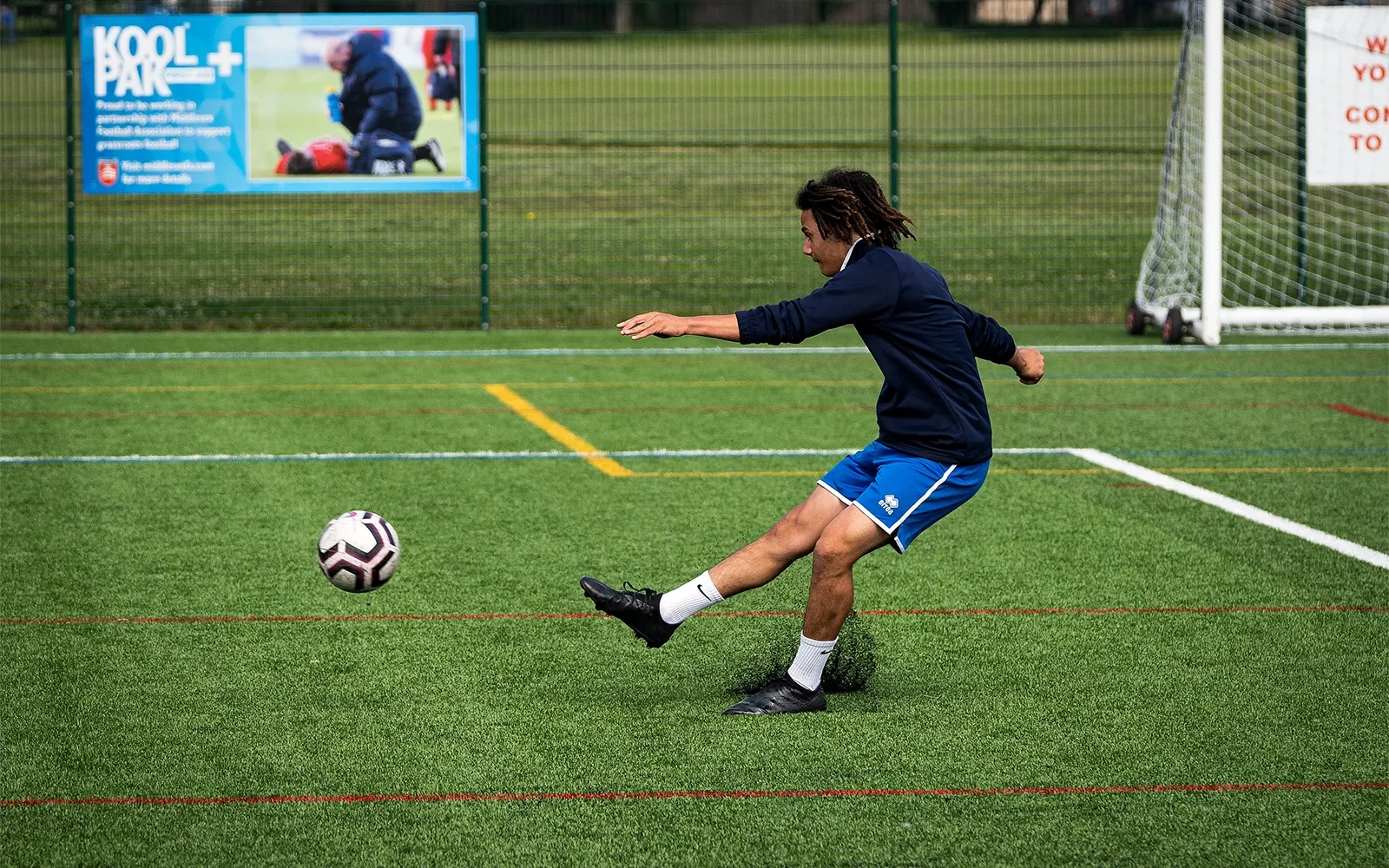 An action shot of a teenage boy during a football training session at a football pitch