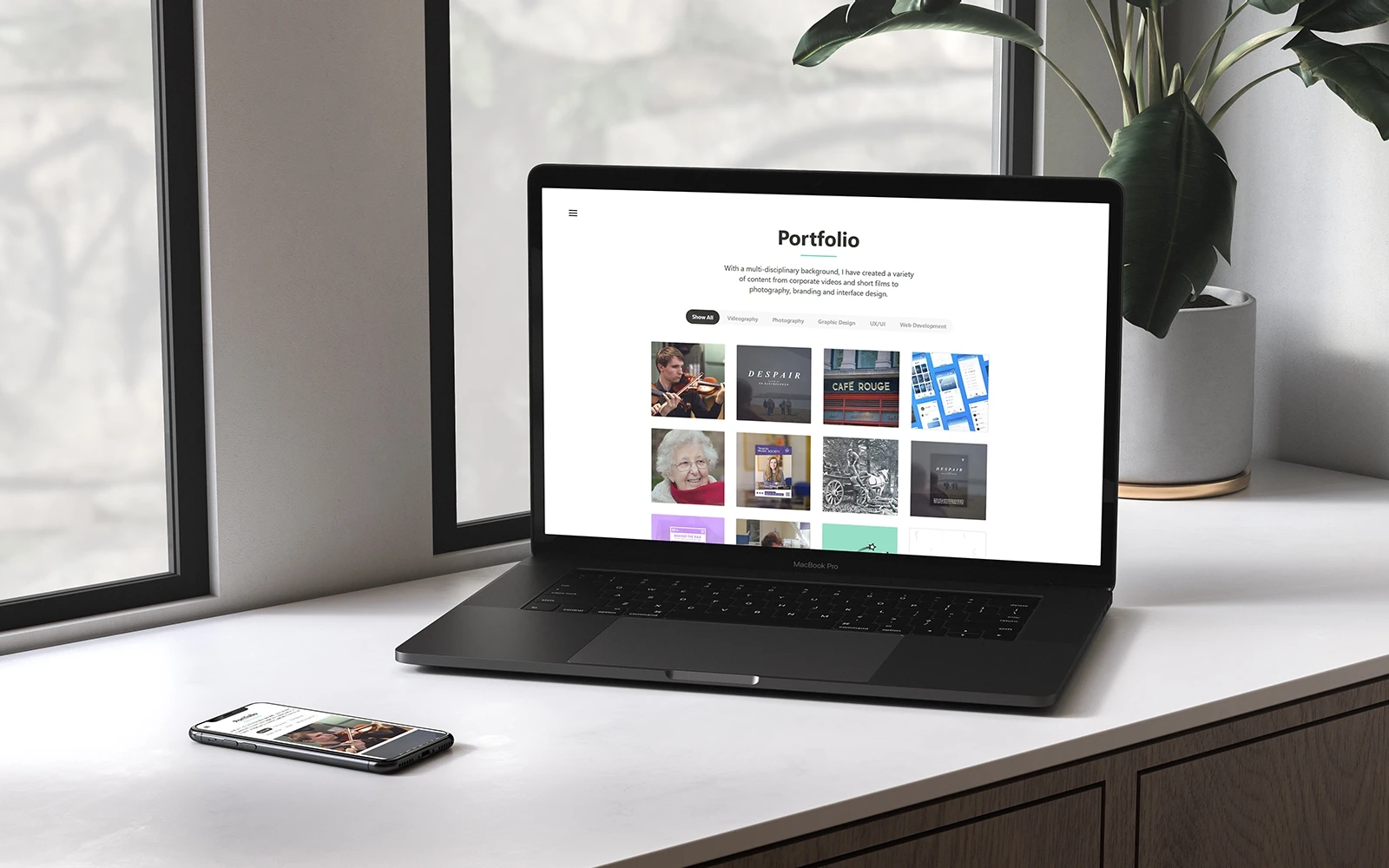 A laptop with the portfolio page displayed with a mobile next to it also displaying the portfolio page of the Ed Bartholomew website, in a clean and modern interior