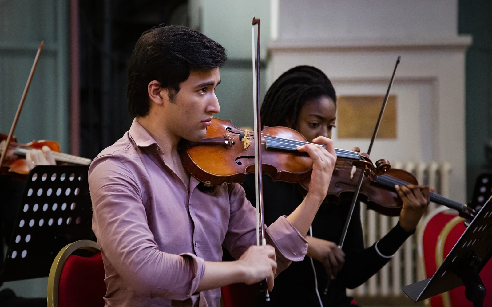 Close up of a young man playing the violin during a concert rehearsal